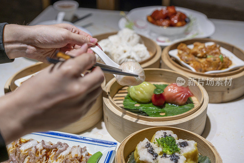 人们用筷子和勺子吃广东dum sum虾饺